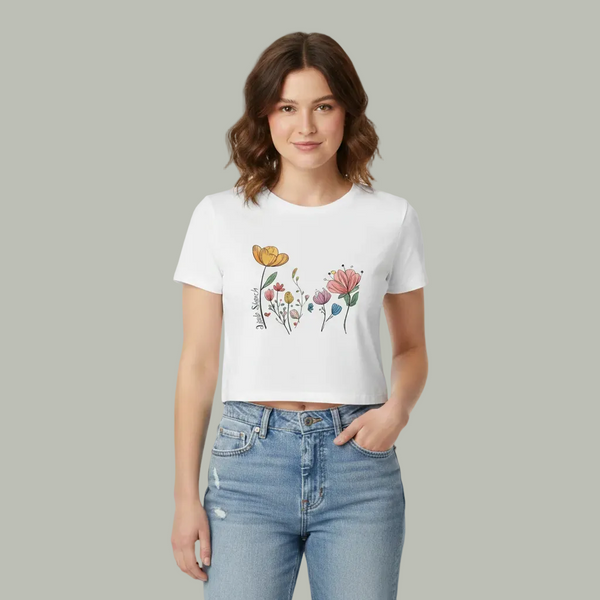 Woman wearing a white t-shirt with floral design and blue jeans on a gray background